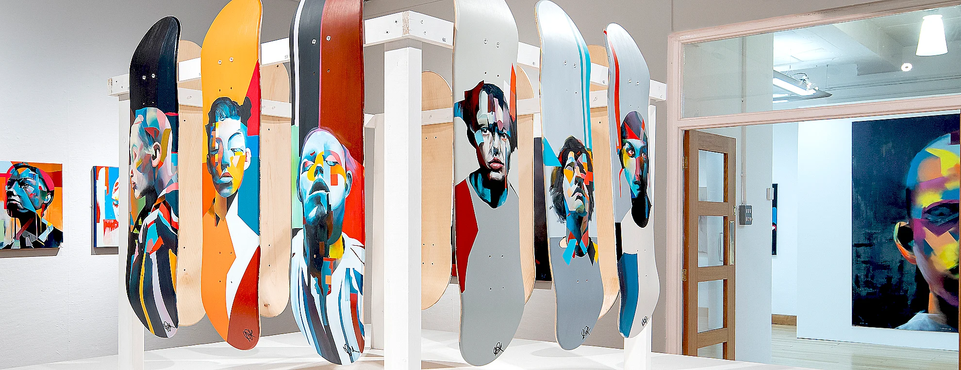 Abstract portrait artworks by Paul Kneen displayed in exhibition with multiple layered faces and bold geometric colour