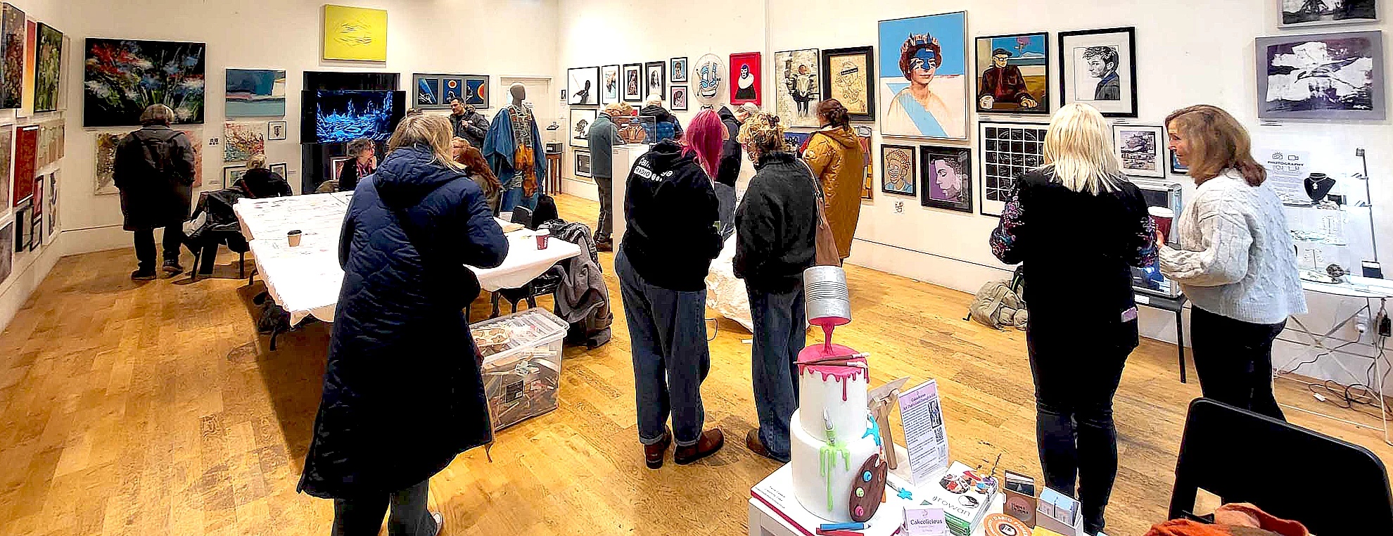Visitors viewing artworks at group exhibition in Cambridge with gallery space and mixed artworks on display