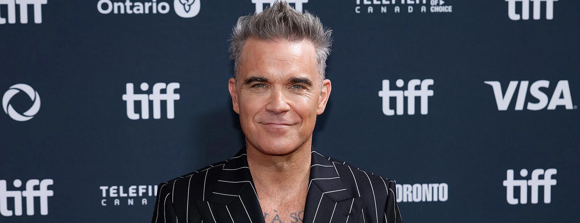 Robbie Williams photographed at a public event for article about celebrity artists and authenticity