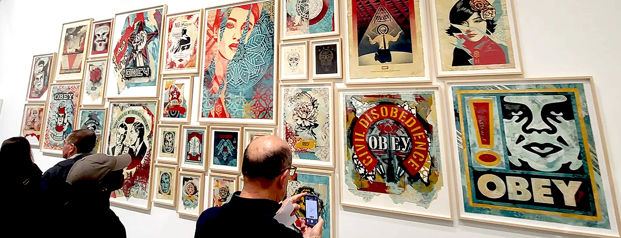 Visitors viewing Shepard Fairey artworks at Newport Street Gallery London exhibition with framed prints on display