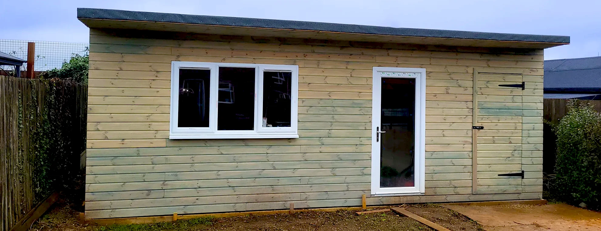 Garden art studio built by Paul Kneen with wooden exterior, window and door in outdoor setting