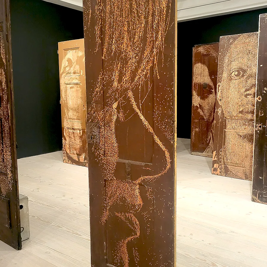 Carved portrait artwork by Vhils on wooden doors installation